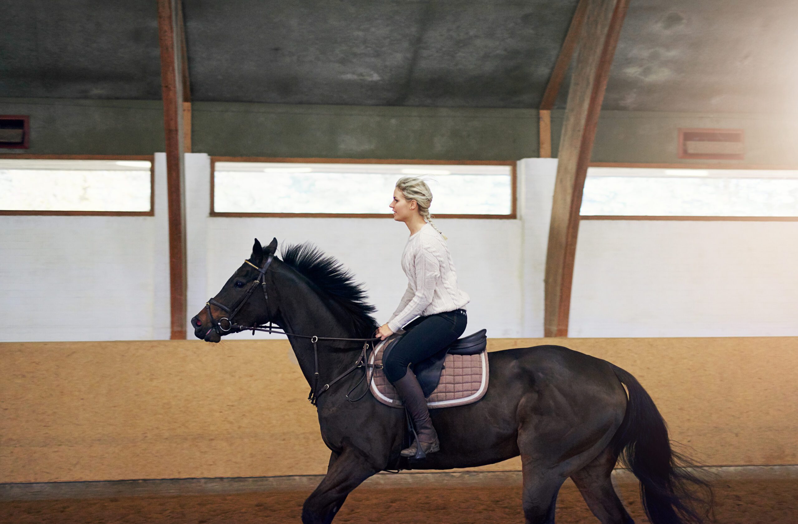 Mujer rubia trotando a caballo